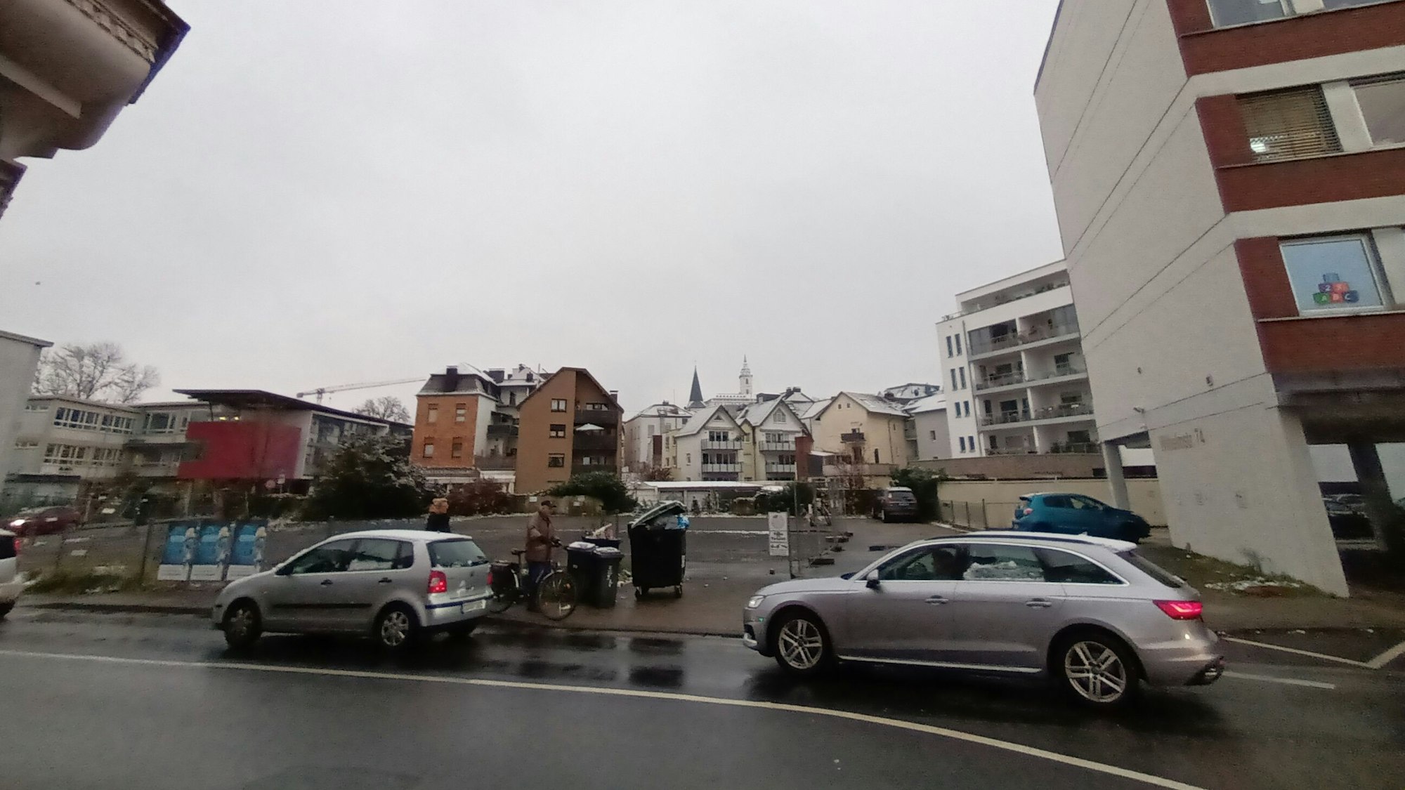 Zwei Autos fahren auf der Straße an dem Baugrundstück in der Sieburger Innenstadt an der Wilhelmstraße vorbei. Das Grundstück liegt zwischen Wohn- und Bürogebäuden und dem Gymnasium Alleestraße.