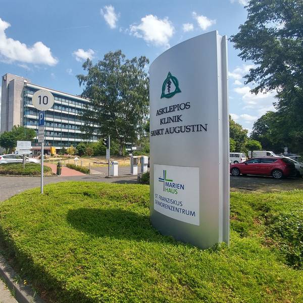 Eine Einfahrt zu einem mehrstöckigen Gebäude, vor dem ein großes Hinweisschild zur Asklepios Kinderklinik steht.