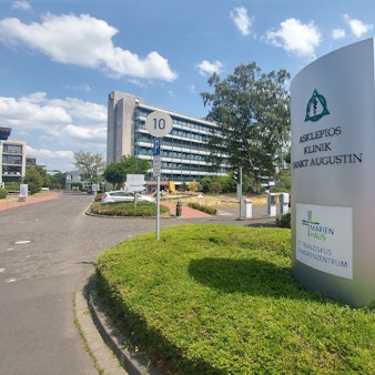 Eine Einfahrt zu einem mehrstöckigen Gebäude, vor dem ein großes Hinweisschild zur Asklepios Kinderklinik steht.