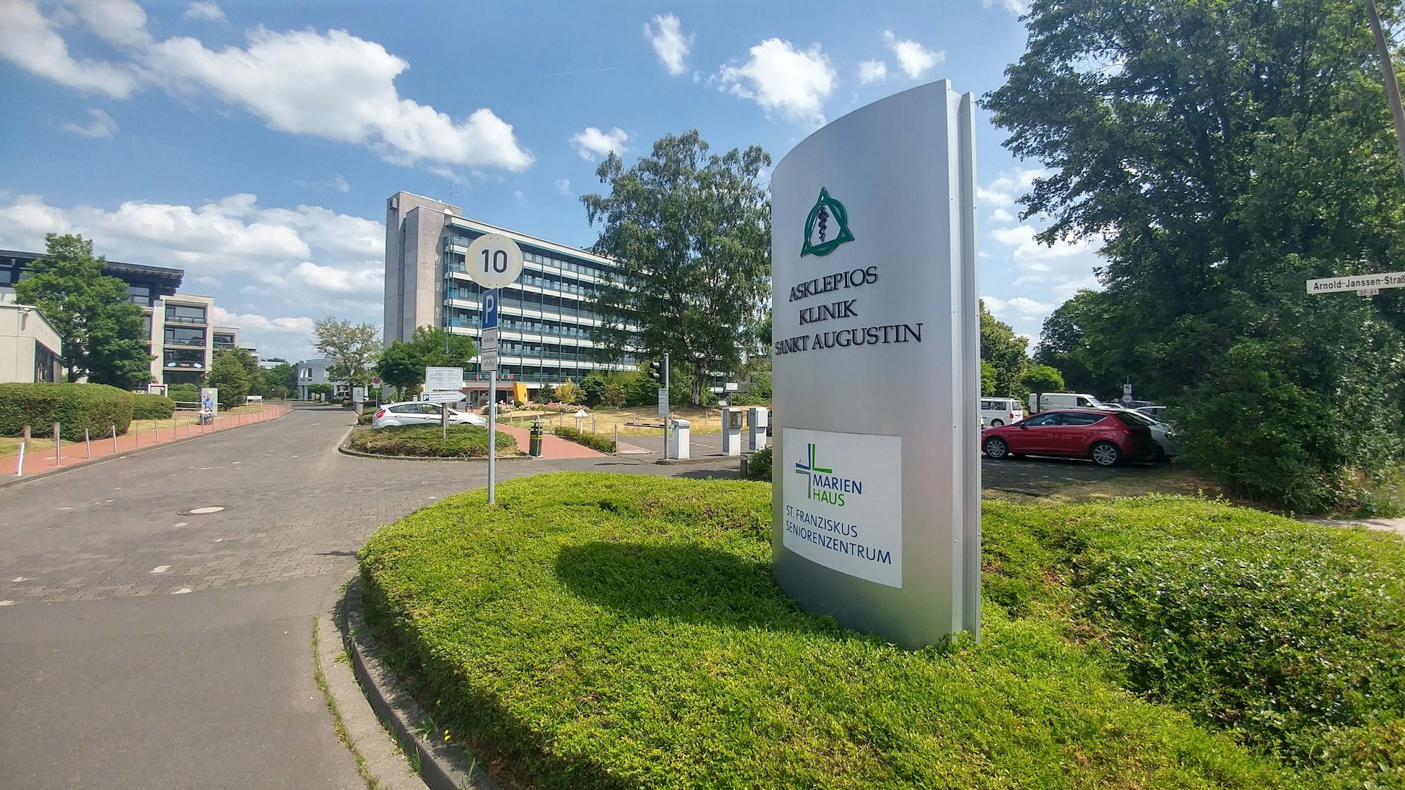 Eine Einfahrt zu einem mehrstöckigen Gebäude, vor dem ein großes Hinweisschild zur Asklepios Kinderklinik steht.