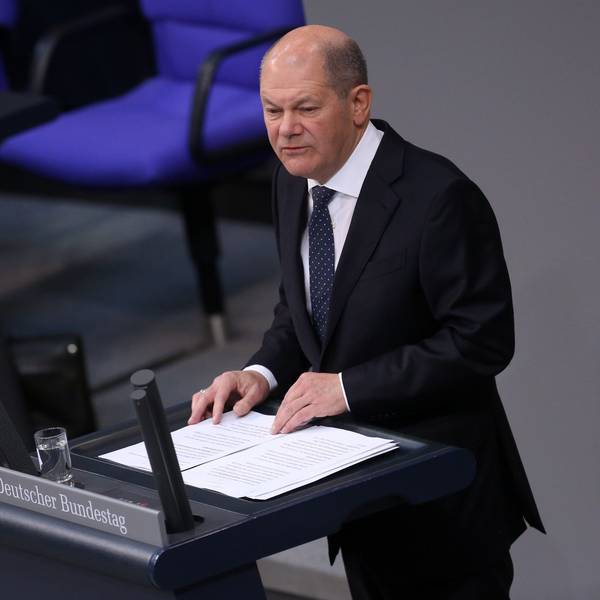Bundeskanzler Olaf Scholz spricht im Deutschen Bundestag. Vor ihm steht ein Glas Wasser, er hat seine Rede ausgedruckt vor sich liegen.