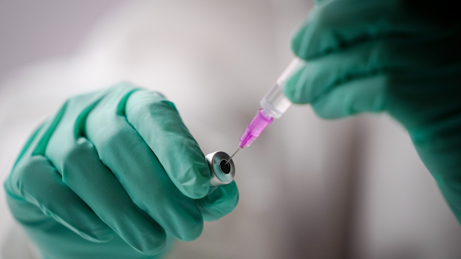 Ein Mitarbeiter in einem Impfzentrum zieht eine Spritze mit dem Impfstoff gegen Covid-19 auf.