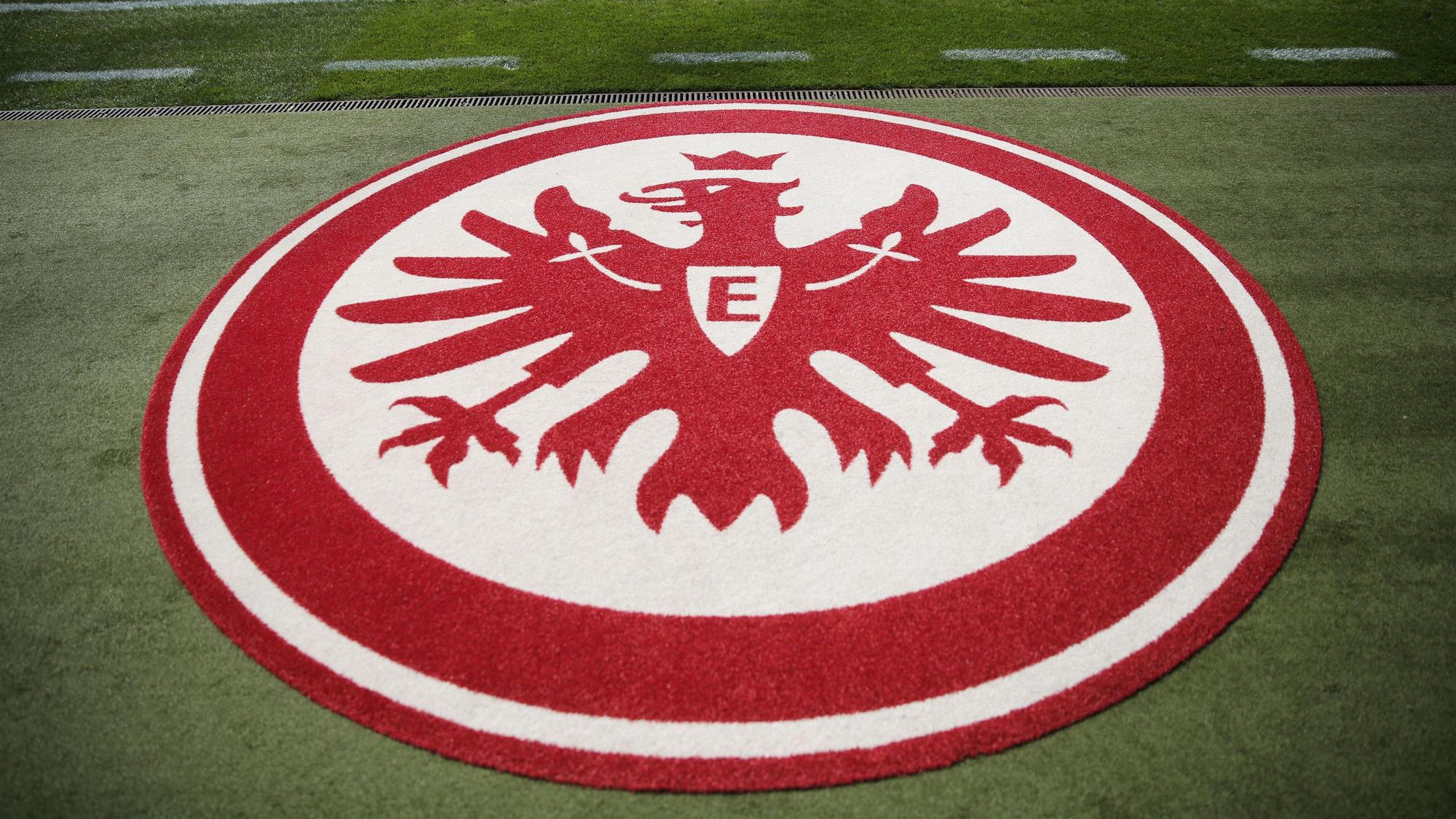 Ein Vereinswappen von Eintracht Frankfurt aus Teppich liegt auf dem Rasen im Stadion.