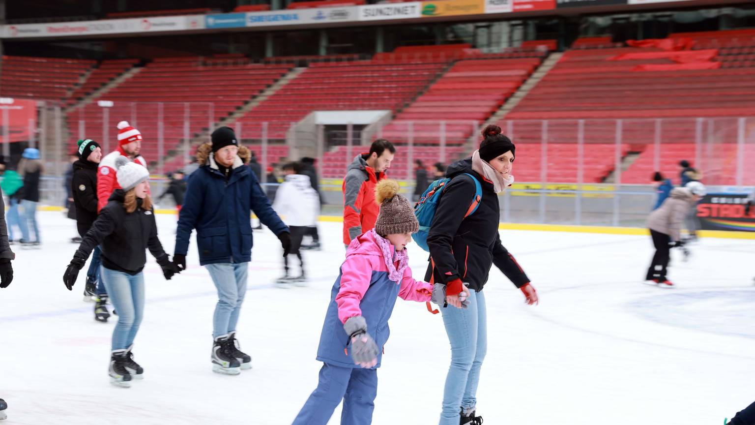 Eine Frau mit einem Kind auf Schlittschuhen im Stadion