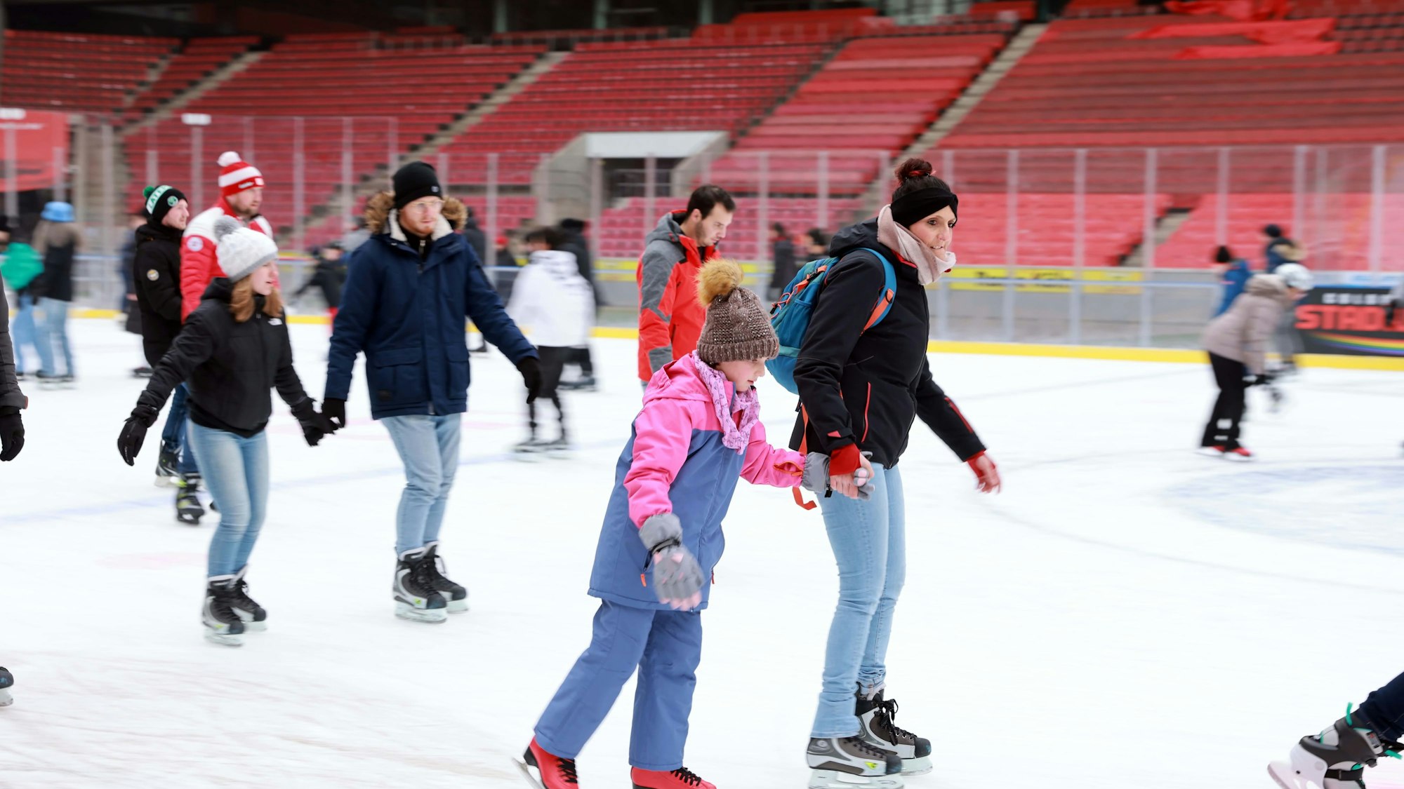 Eine Frau mit einem Kind auf Schlittschuhen im Stadion