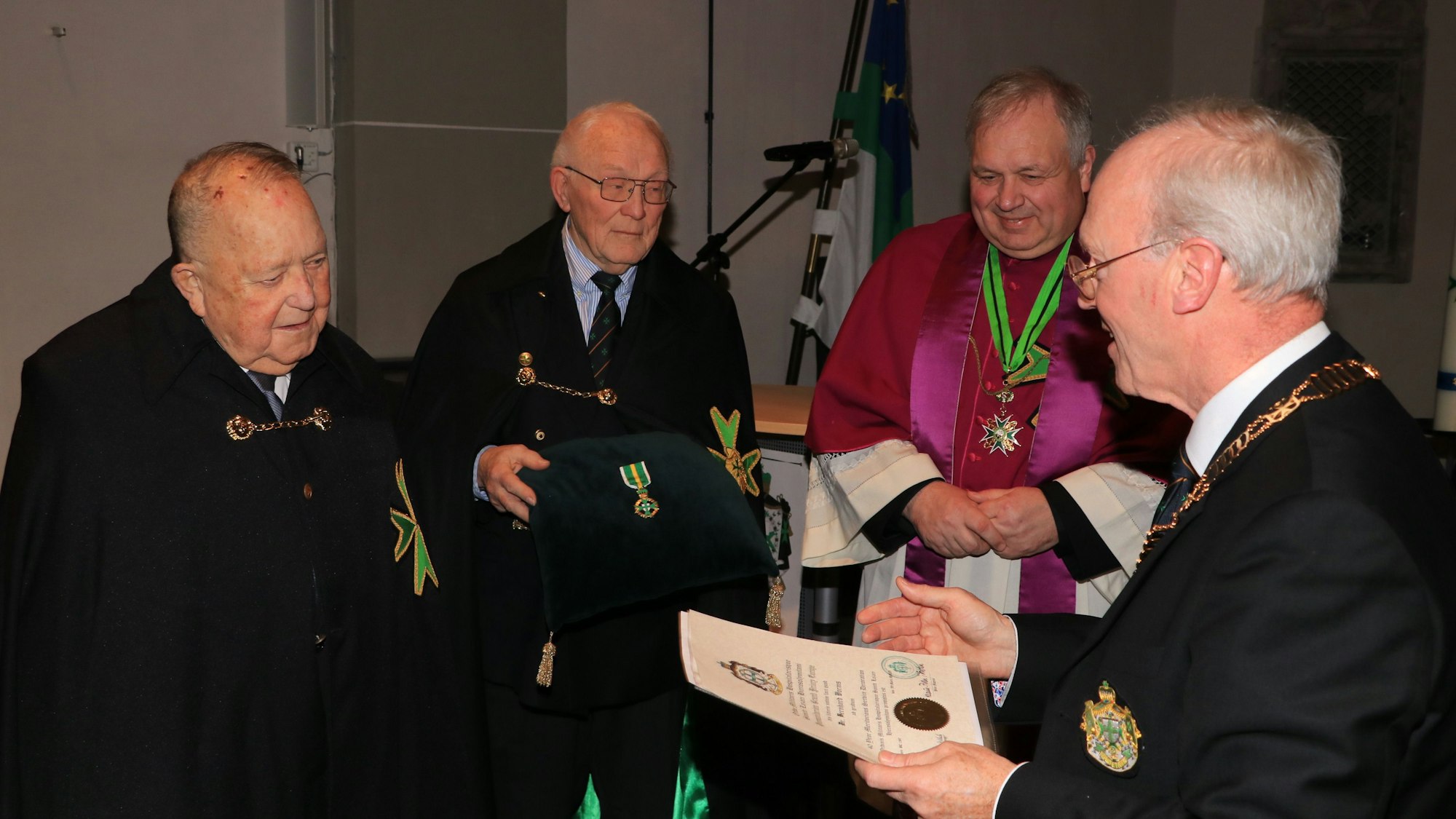 Das Bild zeigt die Übergabe der Urkunde zum Verdienstorden überreicht von Großprior Dr. Rudolf Wansleben an Dr. Bernhard Worms. Im Hintergrund Klaus-Peter Pokolm und Generalkaplan Thorsten Neudenberger.