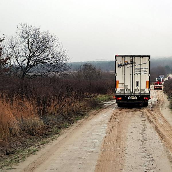 Ein Lkw fährt auf einem braunen Weg in der ukrainischen Landschaft.