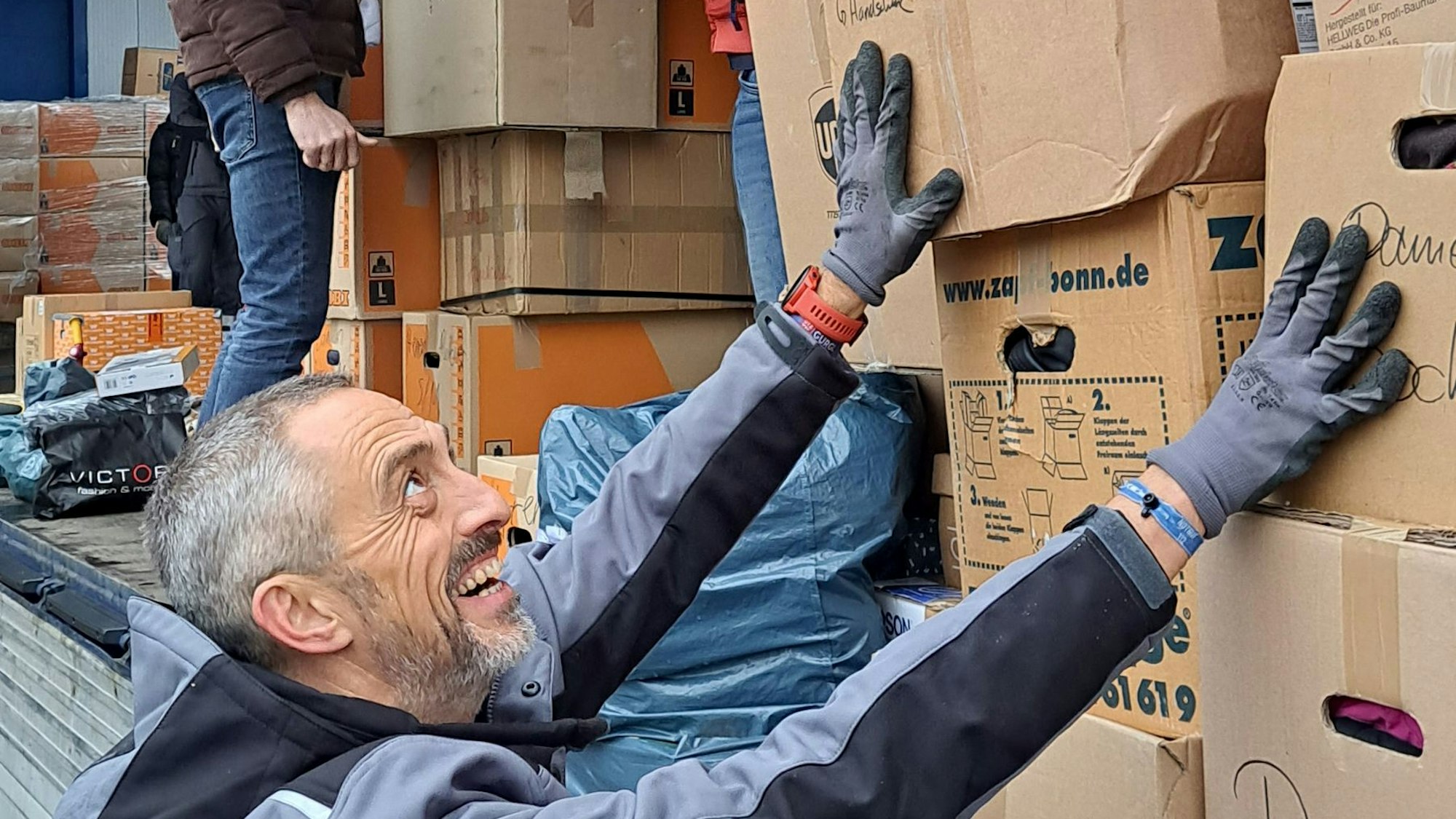 Helfer beladen einen Lkw mit Kartons.