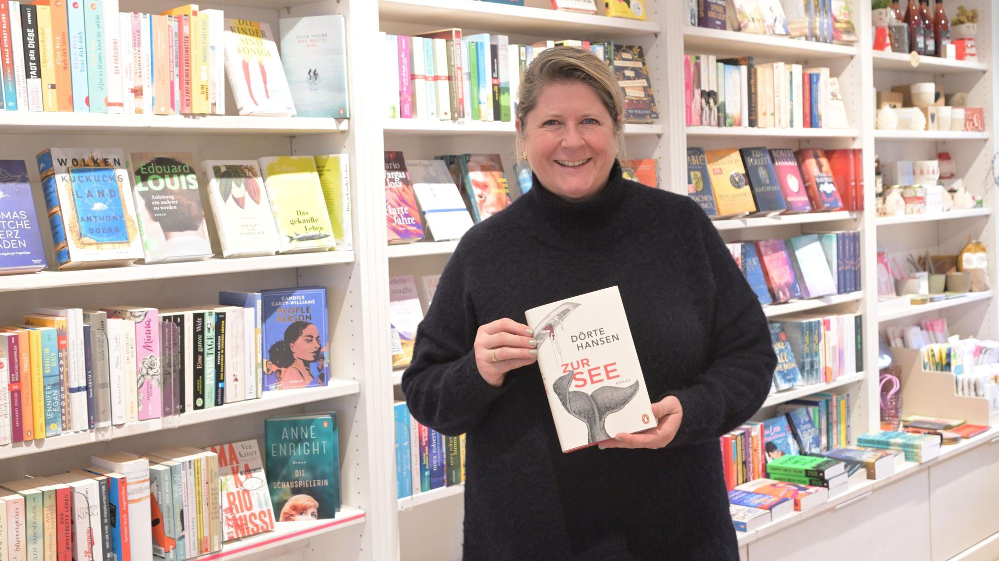 Alexandra Brune-Will steht in ihrem Buchladen und hält den Roman „Zur See“ in die Kamera.