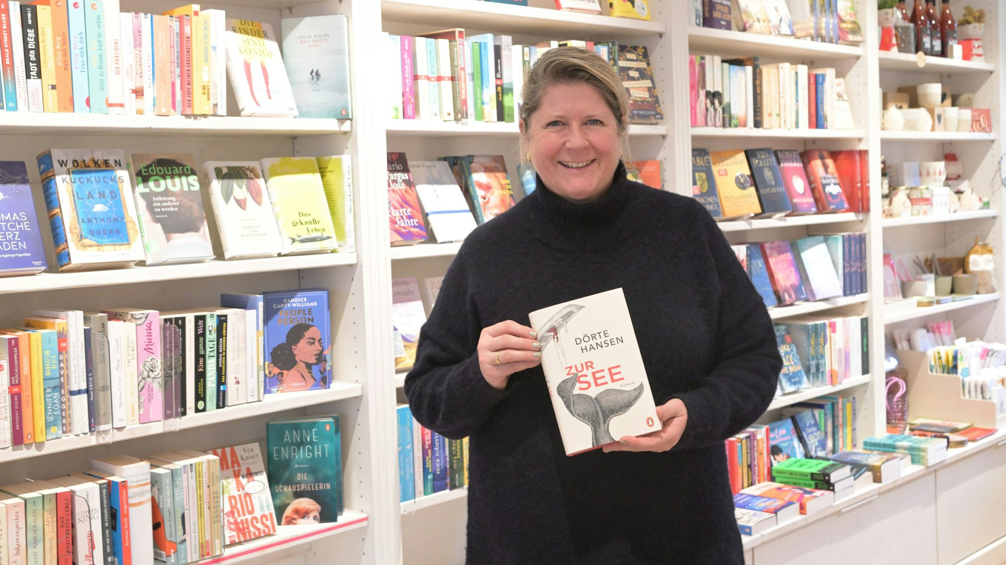 Alexandra Brune-Will steht in ihrem Buchladen und hält den Roman „Zur See“ in die Kamera.