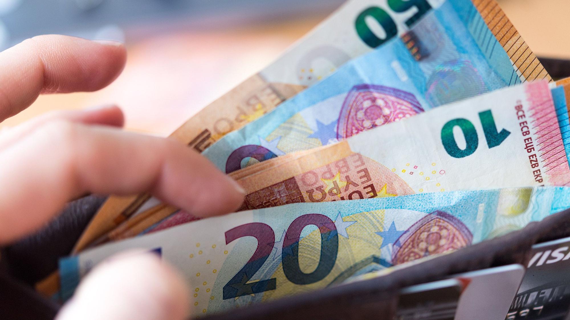 Eine Frau hält eine Geldbörse mit Banknoten in der Hand.