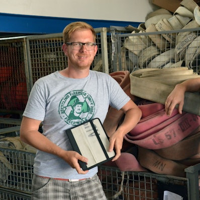 Martin und Robert Klüsener stehen vor alten Feuerwehrschläuchen