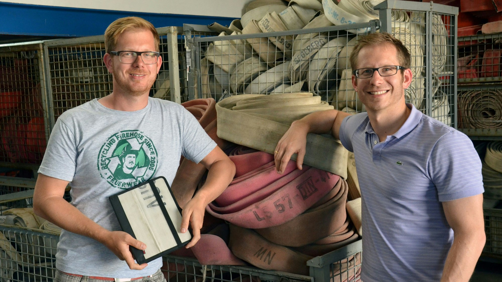 Martin und Robert Klüsener stehen vor alten Feuerwehrschläuchen