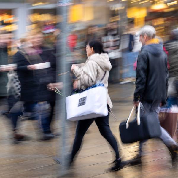 Menschen laufen mit Tüten bepackt durch eine Einkaufsstraße.