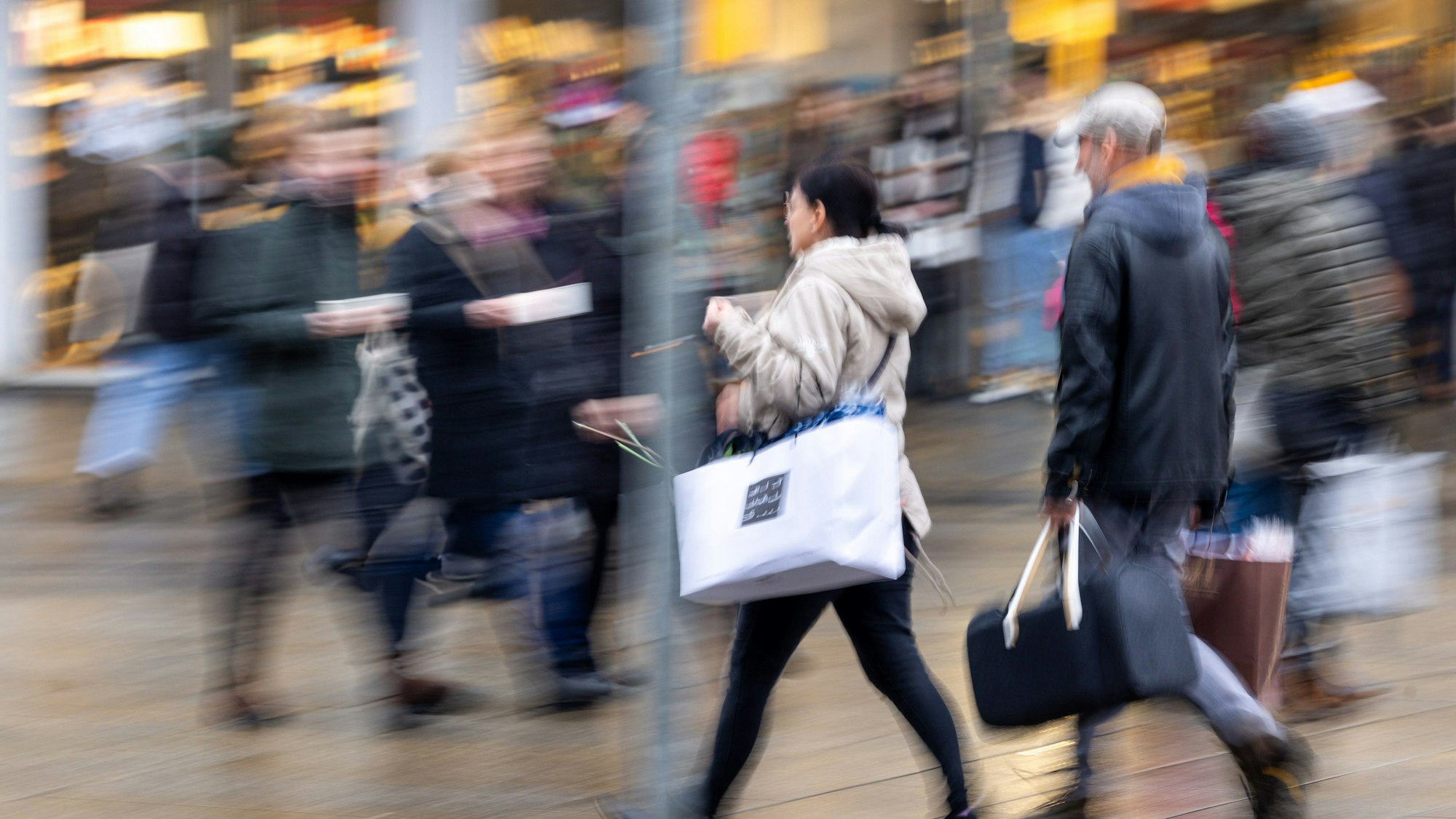 Menschen laufen mit Tüten bepackt durch eine Einkaufsstraße.