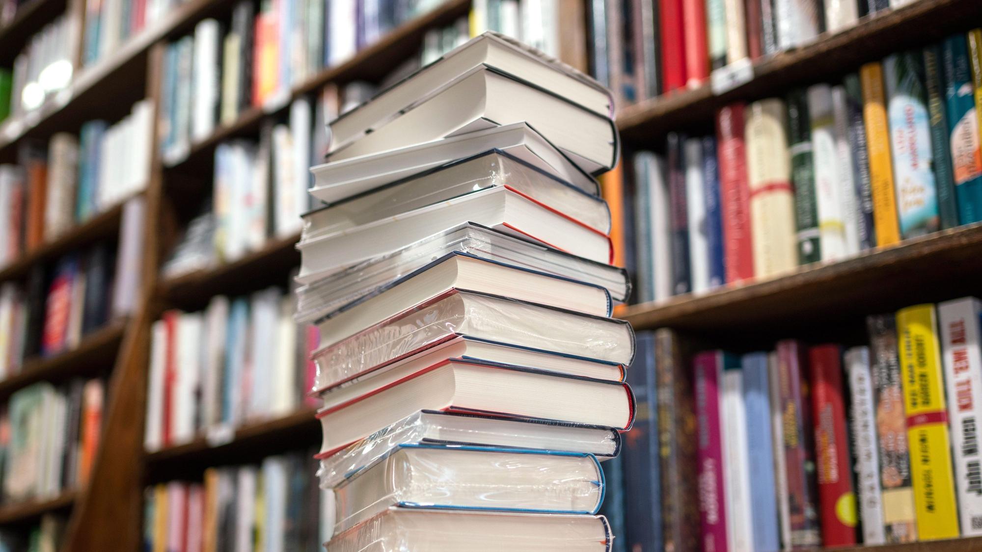 Ein Stapel Bücher liegt auf einem Verkaufstisch in einer Buchhandlung.
