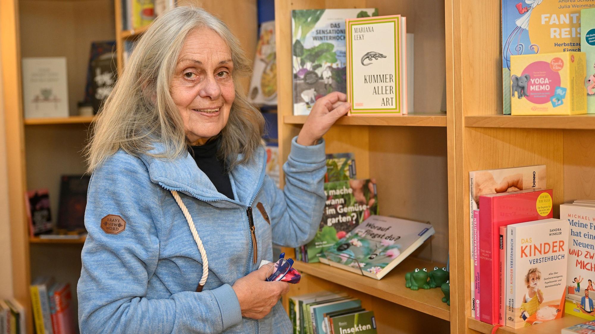 Charlotte Bärenz greift in ein Bücherregal und nimmt sich das Buch „Kummer aller Art“