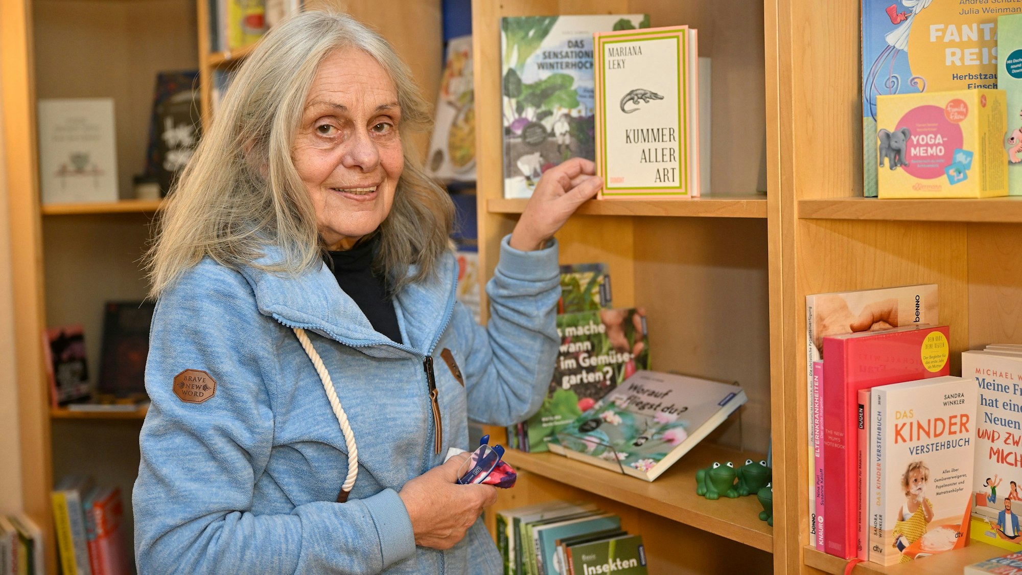 Charlotte Bärenz greift in ein Bücherregal und nimmt sich das Buch „Kummer aller Art“