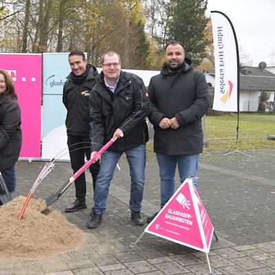 Vier Männer und Bondina Schulze, Bürgermeisterin von Rösrath, stoßen symbolisch einen Spaten in ein Sandhäufchen, aus dem Glasfasern ragen.