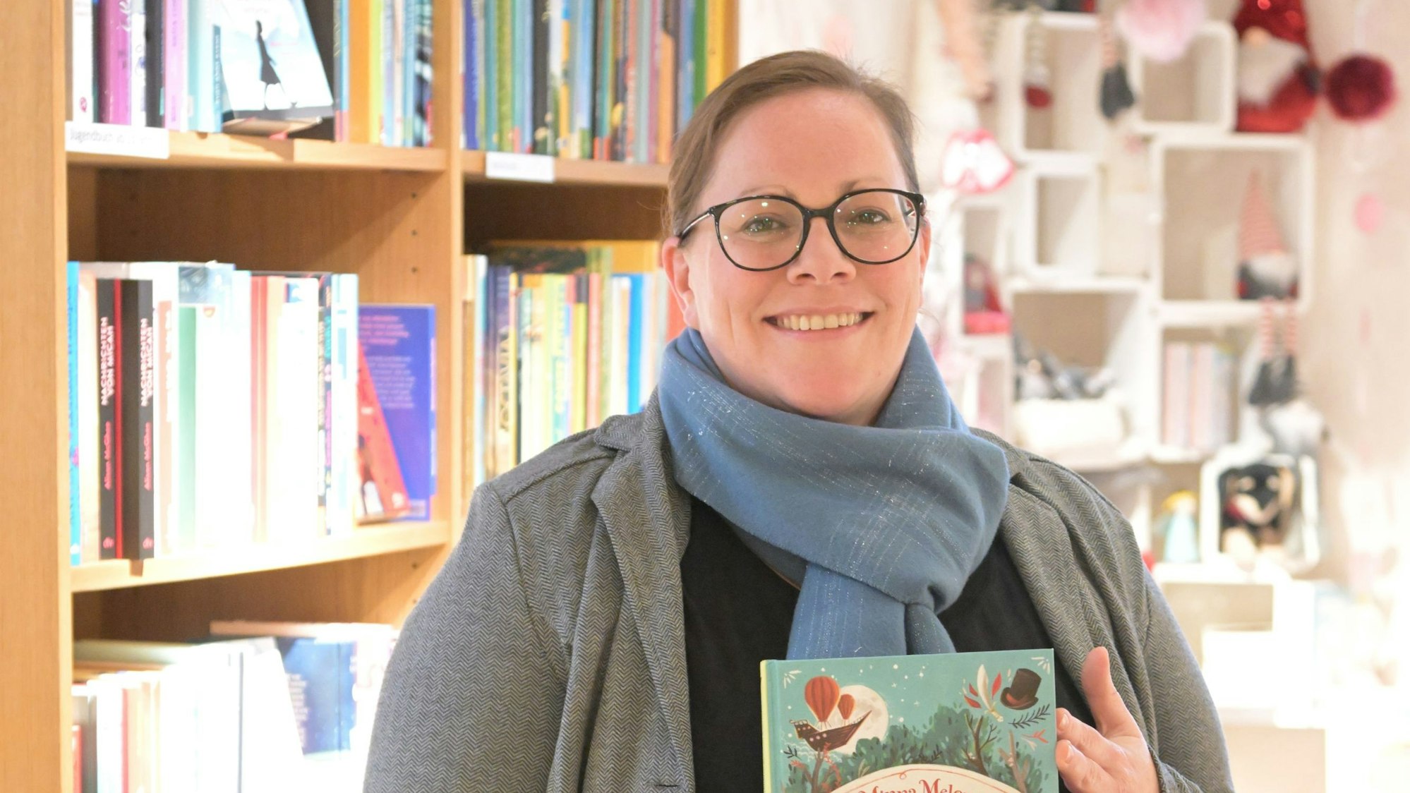 Sandra Jennischek steht im Altenberger-Dom-Laden und hält ein Kinderbuch in der Hand.