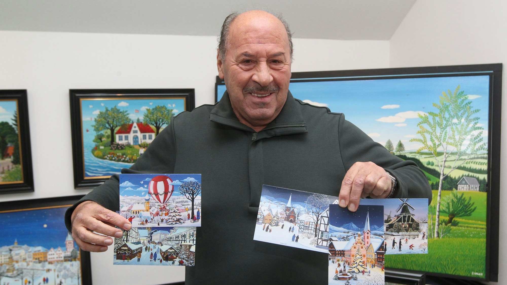 Der Troisdorfer Maler Josef Hawle hält seine fünf Motive für Unicef in der Hand.