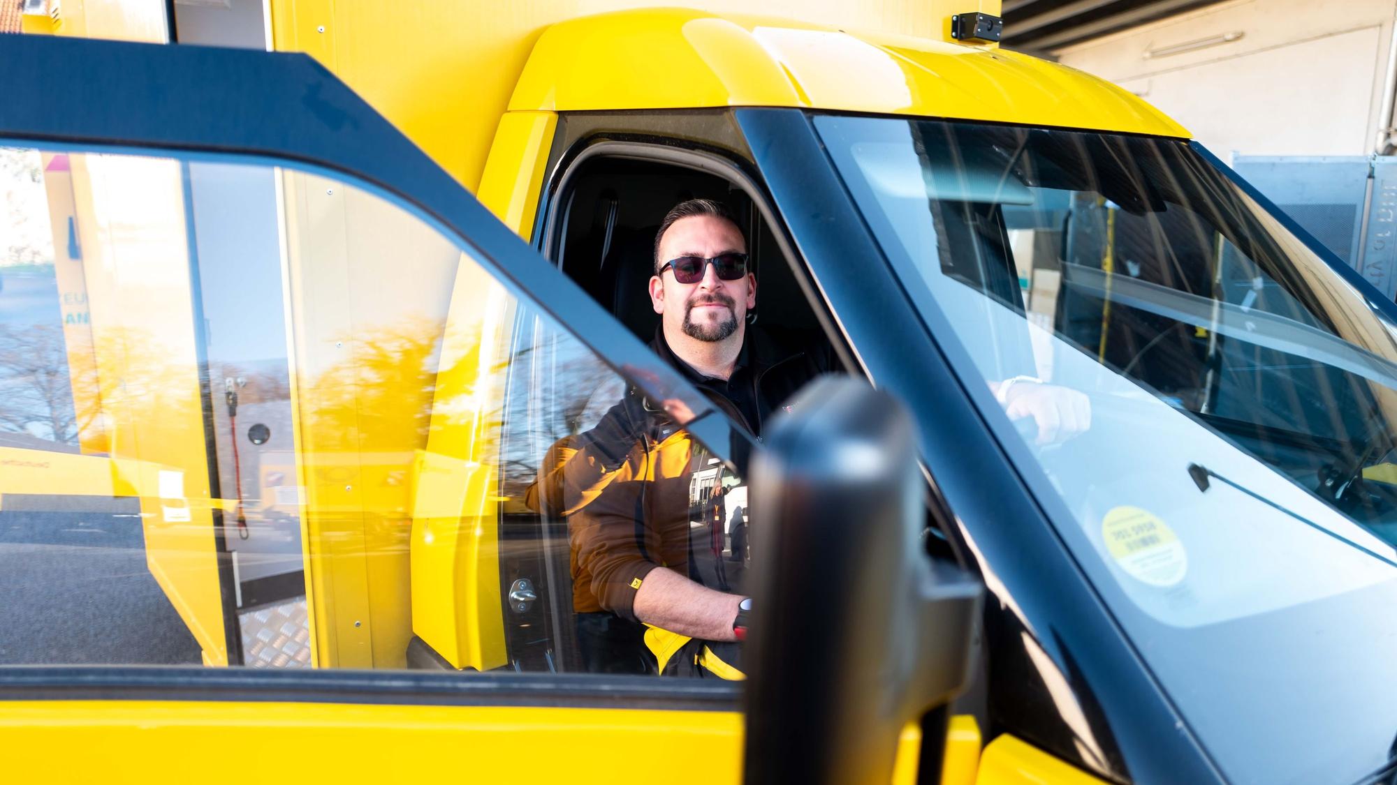 Zusteller Christoph Kompalka sitzt hinter dem Steuer des neuen Street-Scooter-Gigabox-Rechtslenkers.