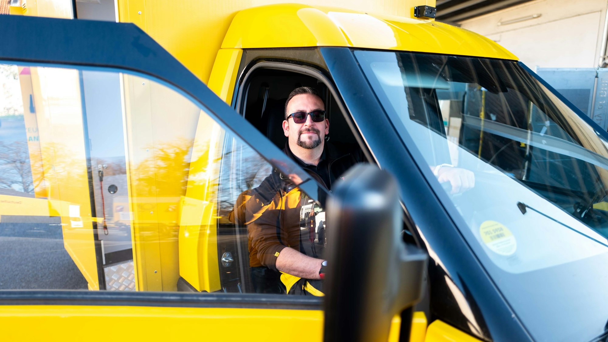 Zusteller Christoph Kompalka sitzt hinter dem Steuer des neuen Street-Scooter-Gigabox-Rechtslenkers.