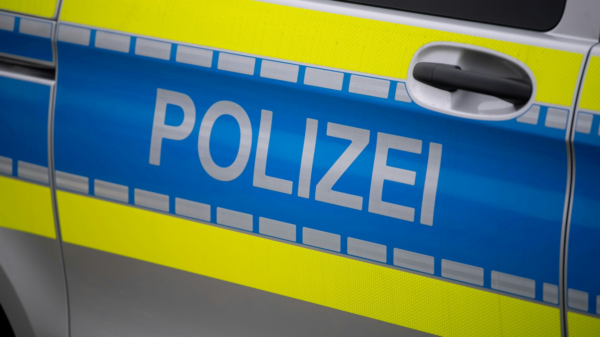 Das Symbolbild zeigt die Tür eines Polizeifahrzeugs mit der Aufschrift Polizei.