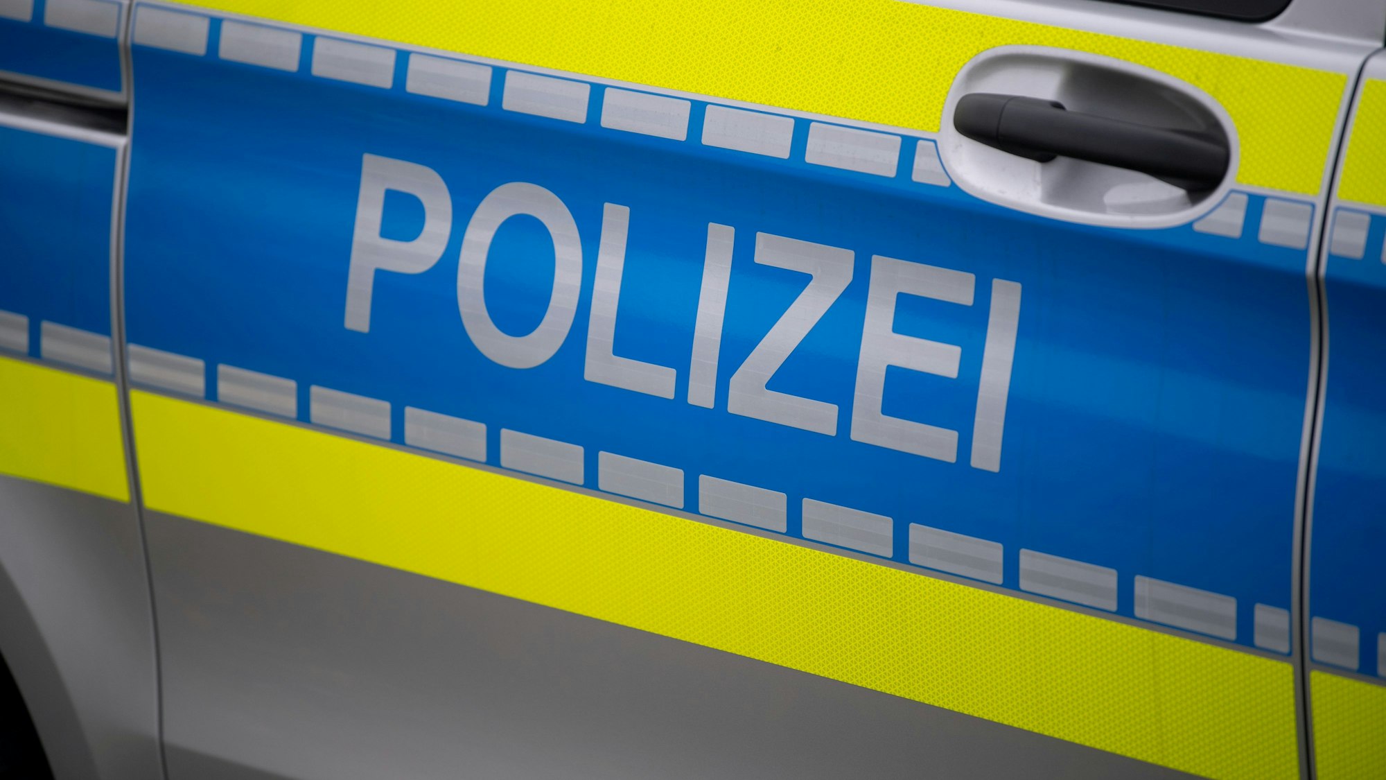 Das Symbolbild zeigt die Tür eines Polizeiautos mit der Aufschrift „Polizei“.
