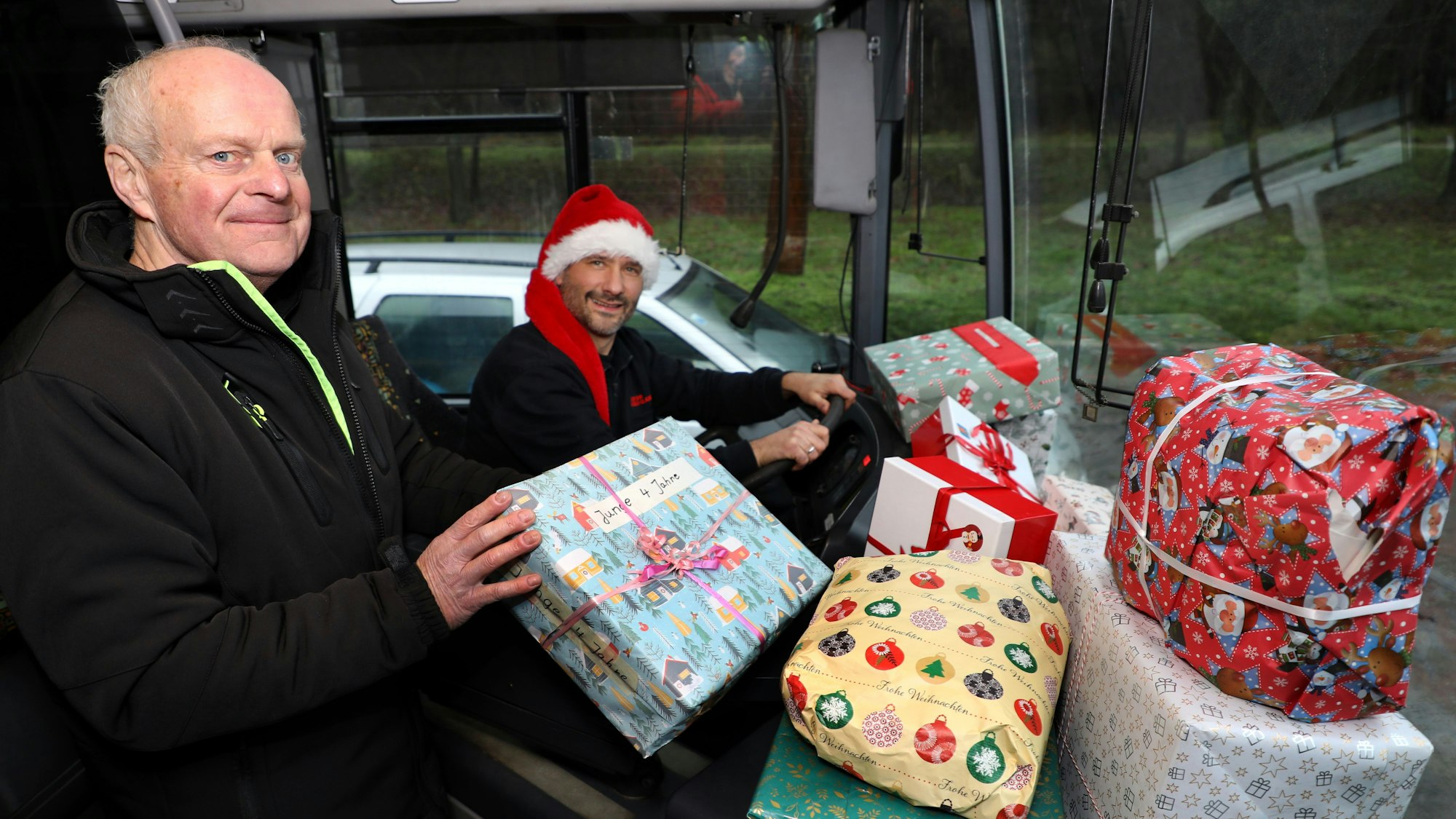 Guido Maria Jansen und Arne Meinhardt im Bus mit bunt verpackten Wichtelgeschenken.
