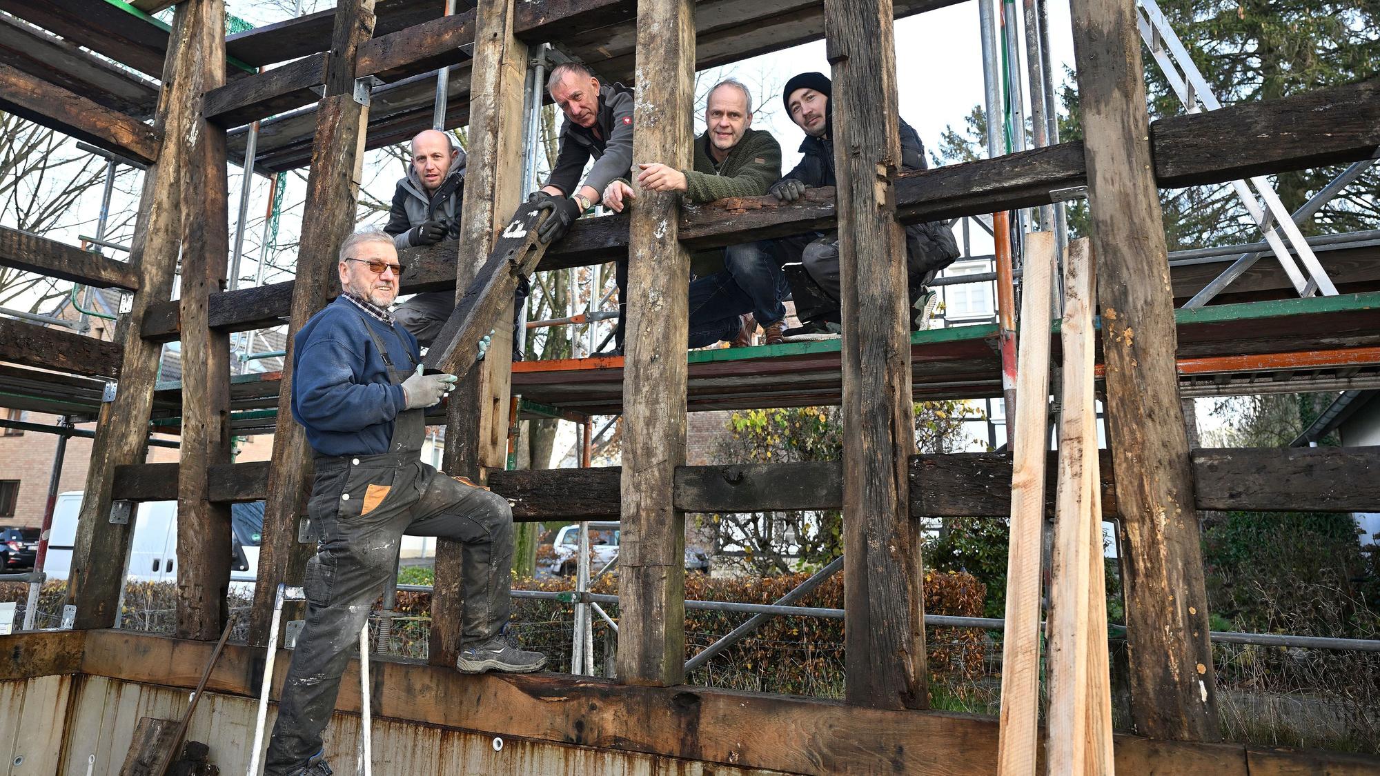 Markus Hetzenegger steht mit vier weiteren Handwerkern zwischen den Holzbalken eines noch unfertigen Fachwerkhauses.