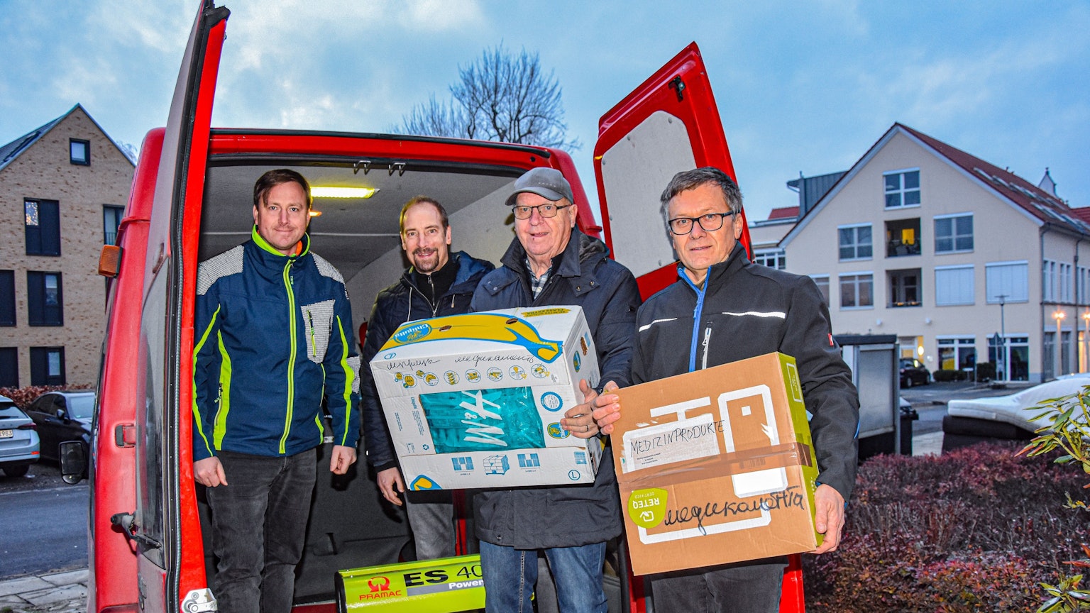 Vier Männer beladen in Rheinbach einen Lieferwagen mit Medizinprodukten und Stromaggregaten.