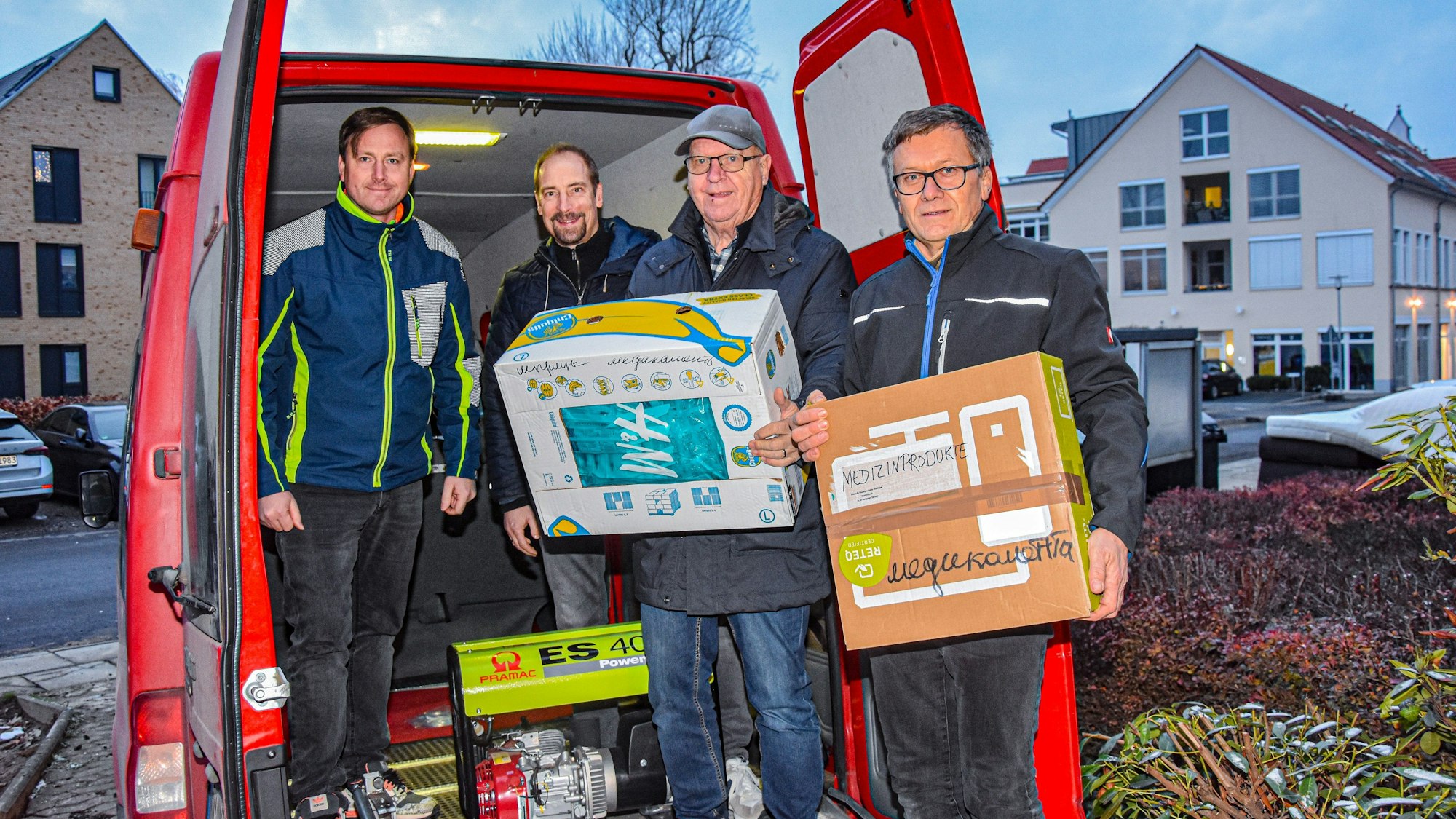 Vier Männer beladen in Rheinbach einen Lieferwagen mit Medizinprodukten und Stromaggregaten.