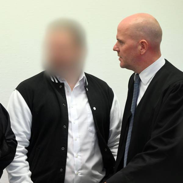 Der Angeklagte steht zwischen seinen Anwälten im Kölner Landgericht.