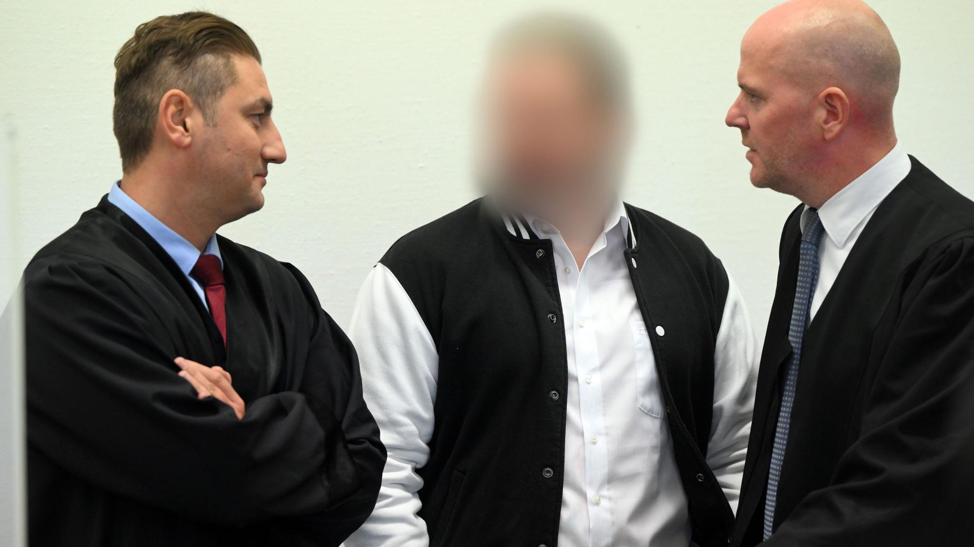 Der Angeklagte steht zwischen seinen Anwälten Mutlu Günal und Martin Bücher.