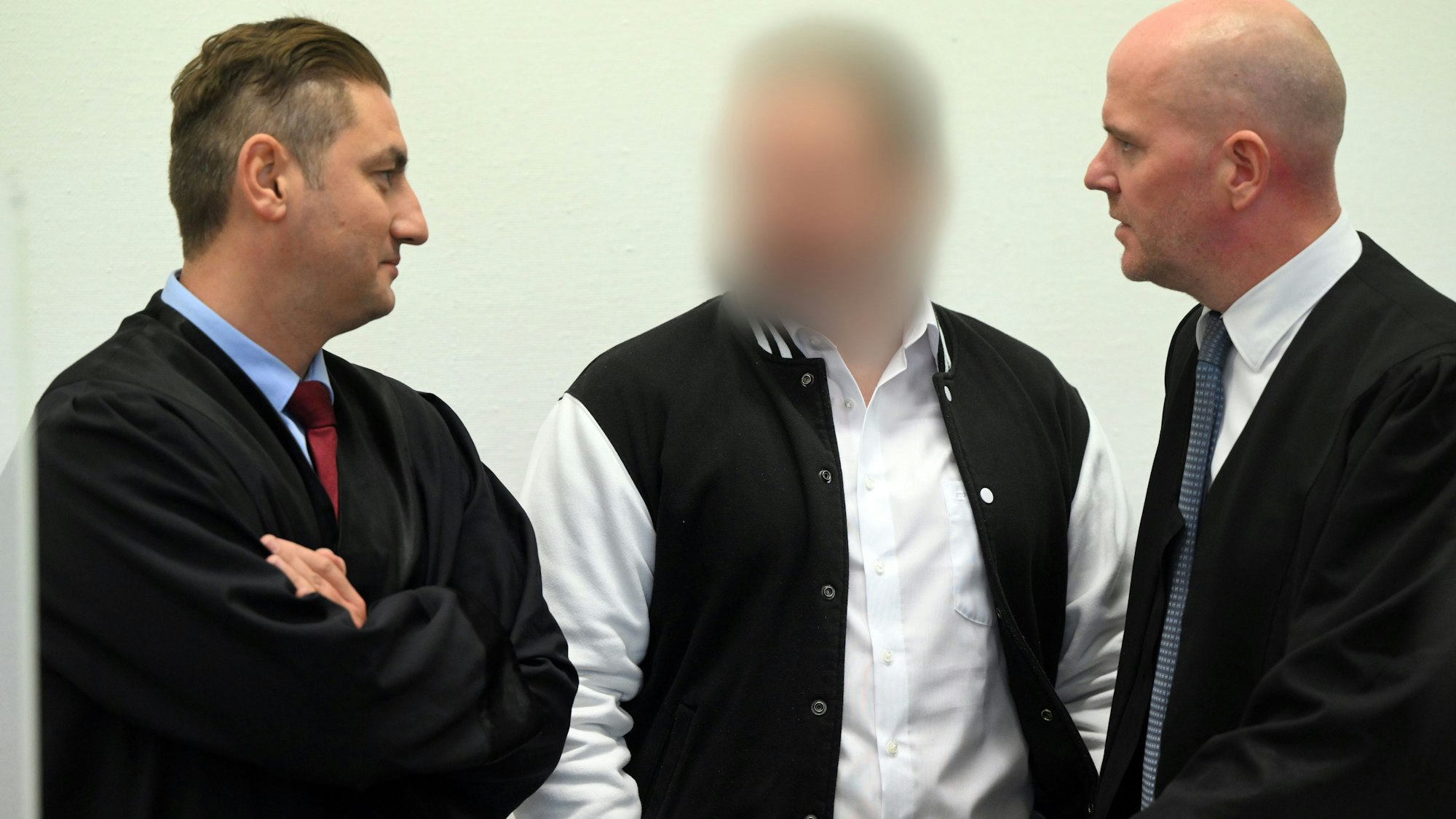 Der Angeklagte steht zwischen seinen Anwälten Mutlu Günal und Martin Bücher.