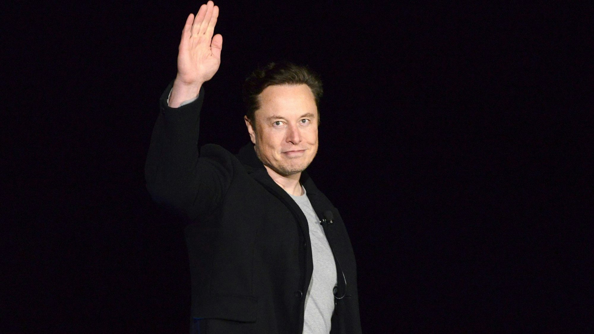 Elon Musk winkt in die Kamera.