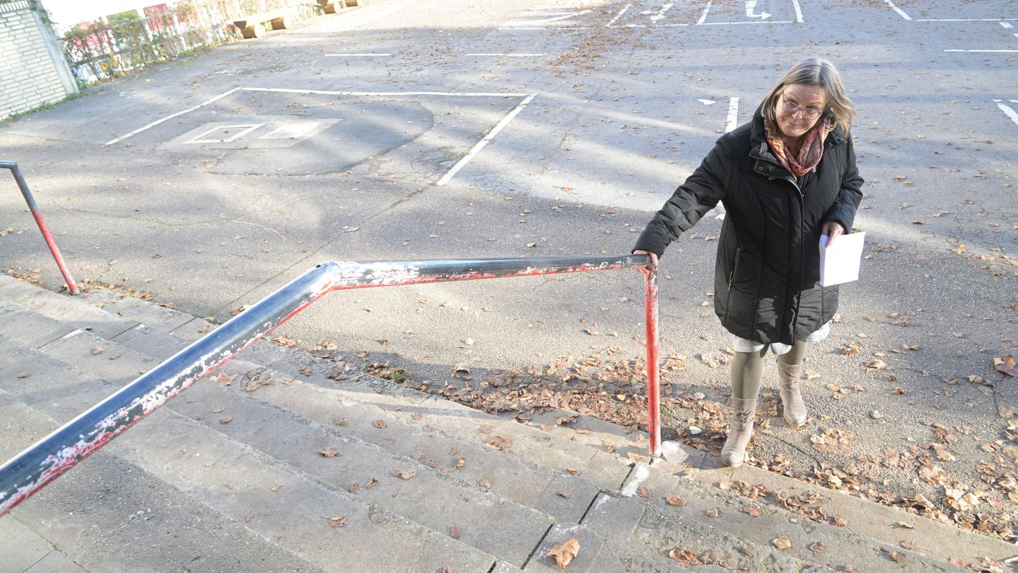 Die Schulleiterin steht vor der Schule am Treppengeländer.
