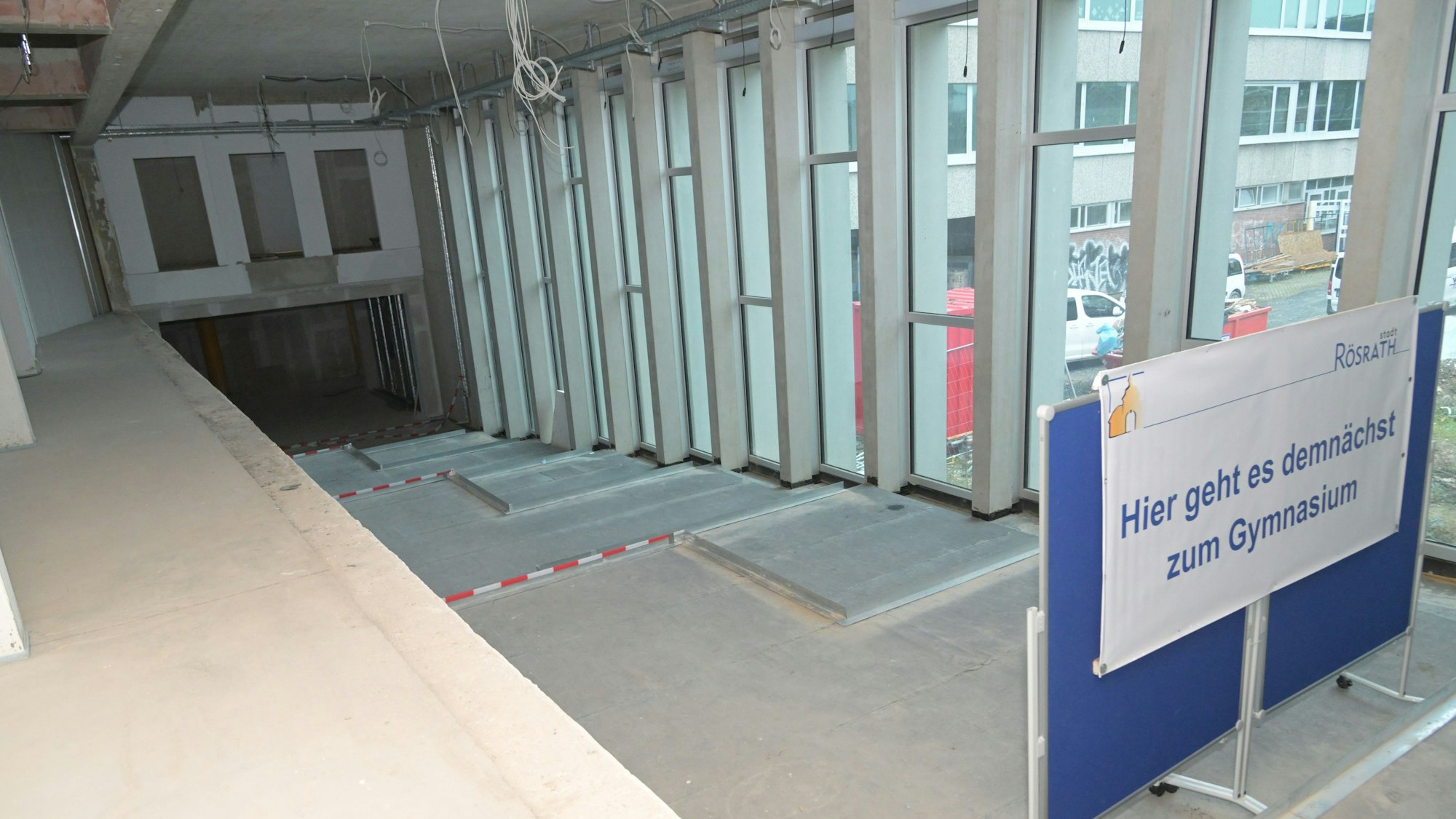 Baustelle im Freiherr-vom-Stein-Gymnasium in Rösrath. Rechts ein Schild mit der Aufschrift „Hier geht es demnächst zum Gymnasium“.