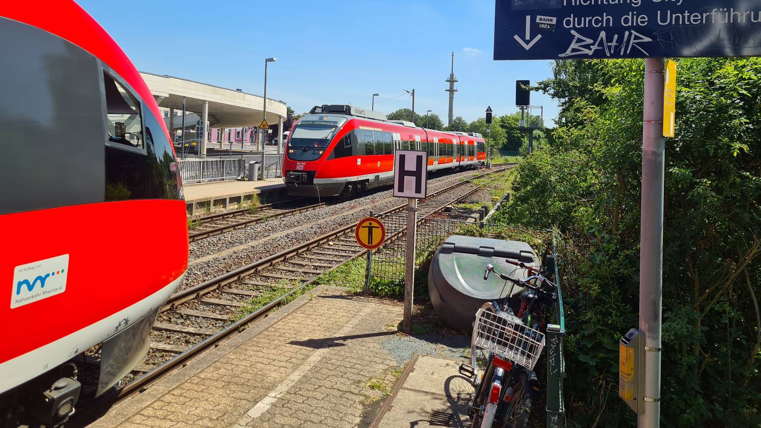 Am Bahnhof Bergheim begegnen sich zwei rote Regionalbahnen.