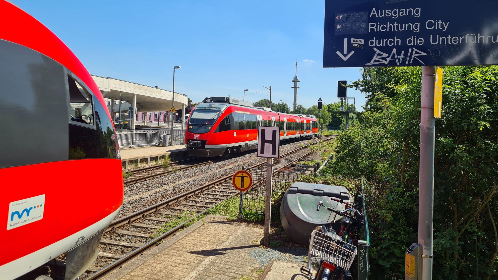 Am Bahnhof Bergheim begegnen sich zwei rote Regionalbahnen.