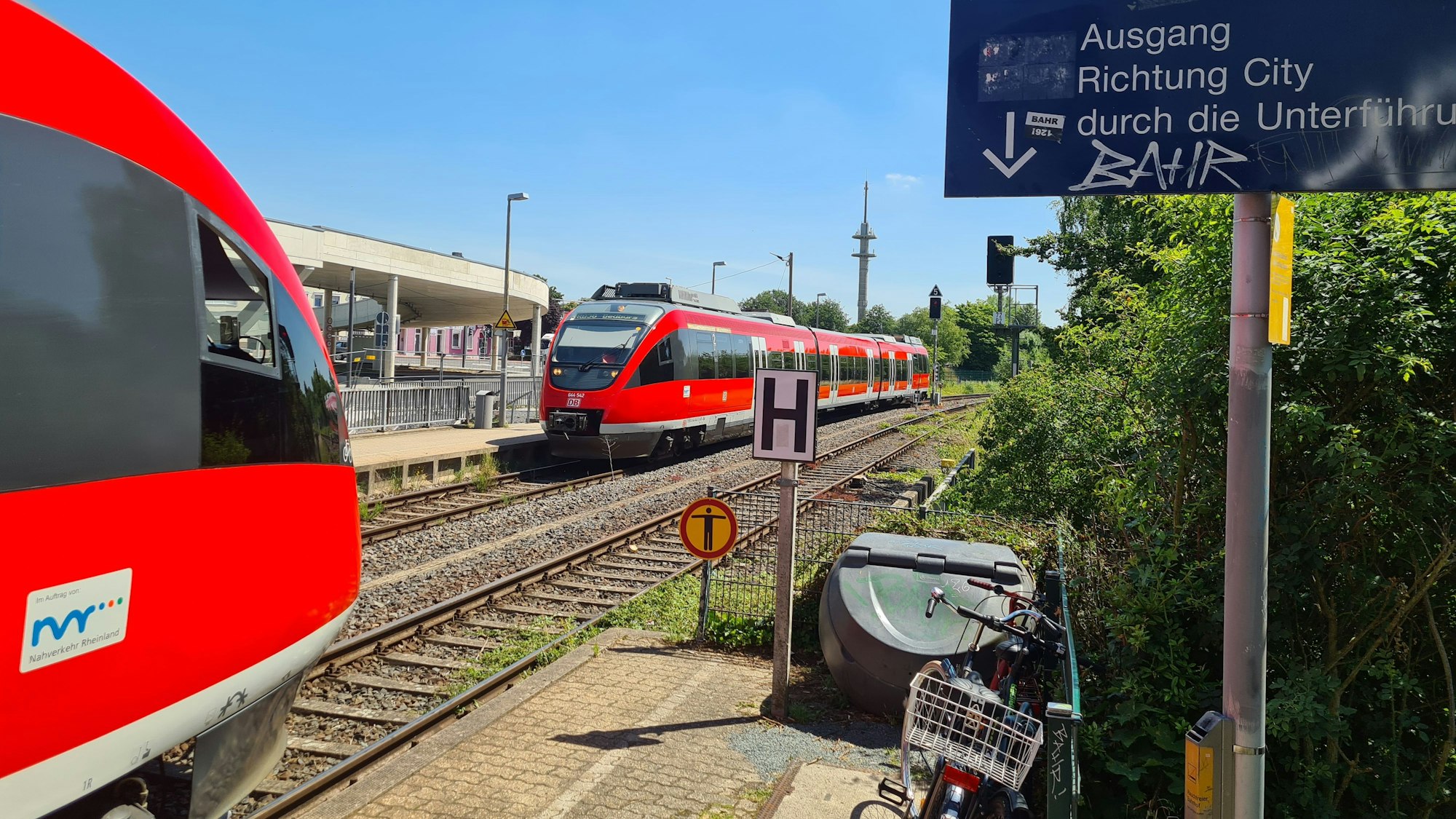 Am Bahnhof Bergheim begegnen sich zwei rote Regionalbahnen.