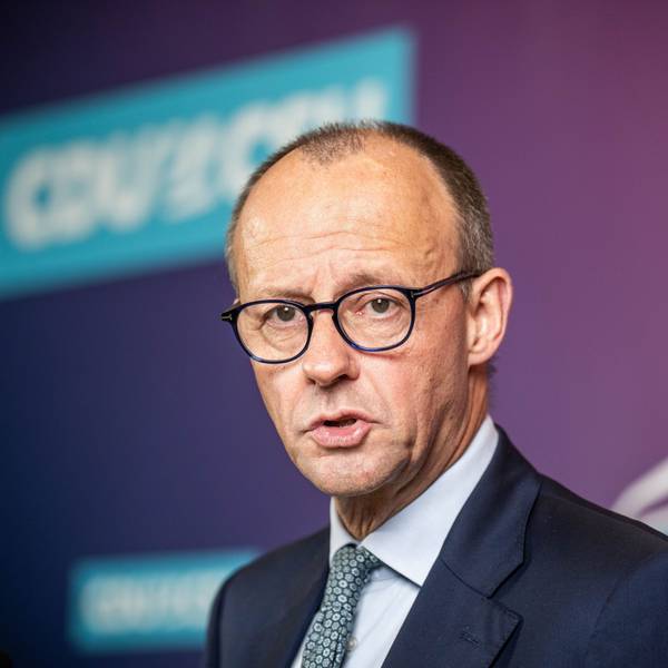 Friedrich Merz steht in dunkelblauem Anzug vor einer Wand, er blickt besorgt.