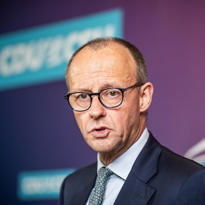 Friedrich Merz steht in dunkelblauem Anzug vor einer Wand, er blickt besorgt.