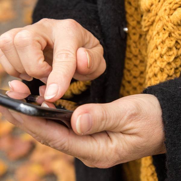 Eine Person hält ein Smartphone in der Hand und tippt darauf.