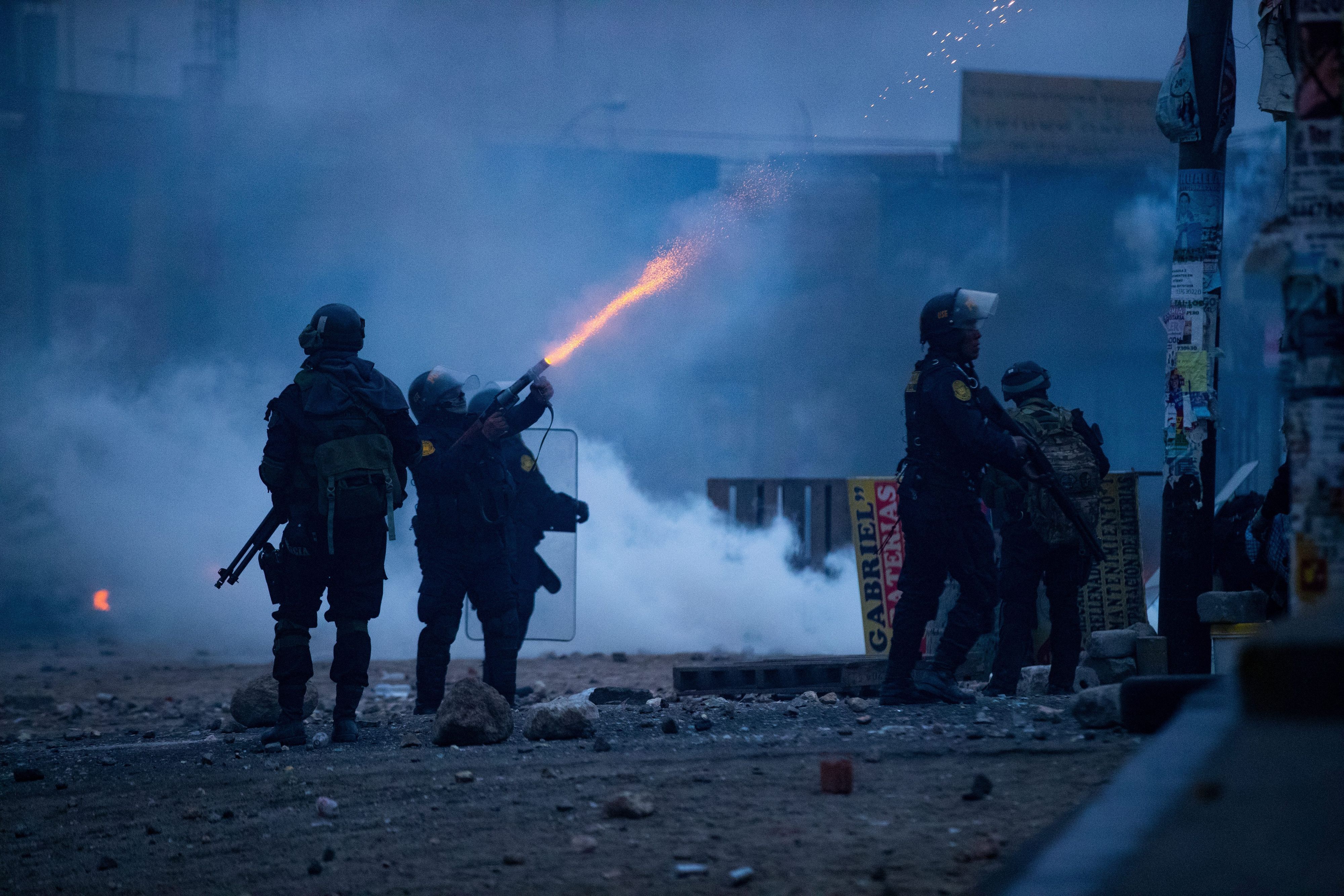 Peru, Arequipa: Ein Polizist feuert Tränengas in Richtung von Demonmstranten während eines Protests.