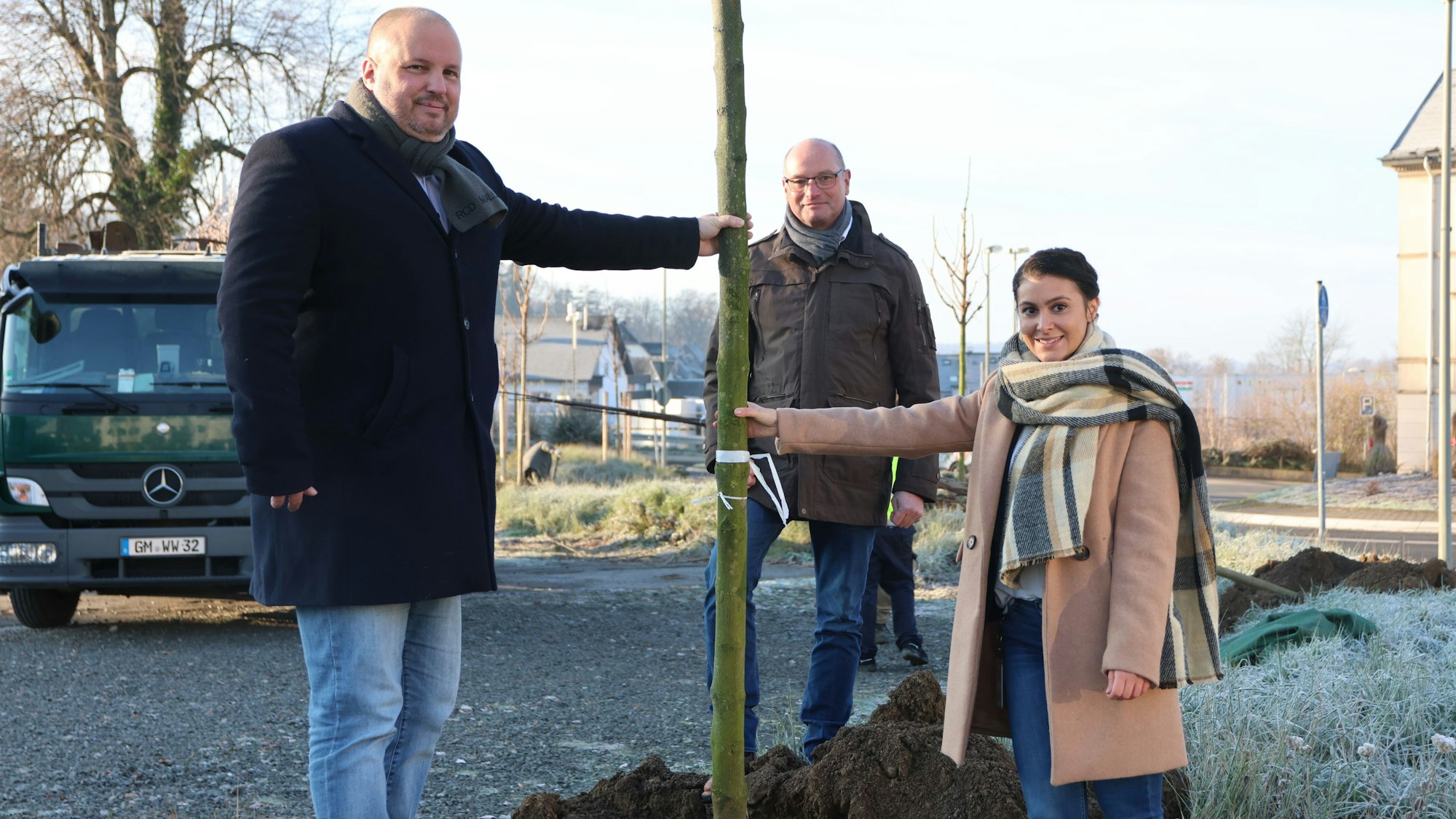 Zwei Männer und eine Frau pflanzen einen Baum in Bergneustadt.