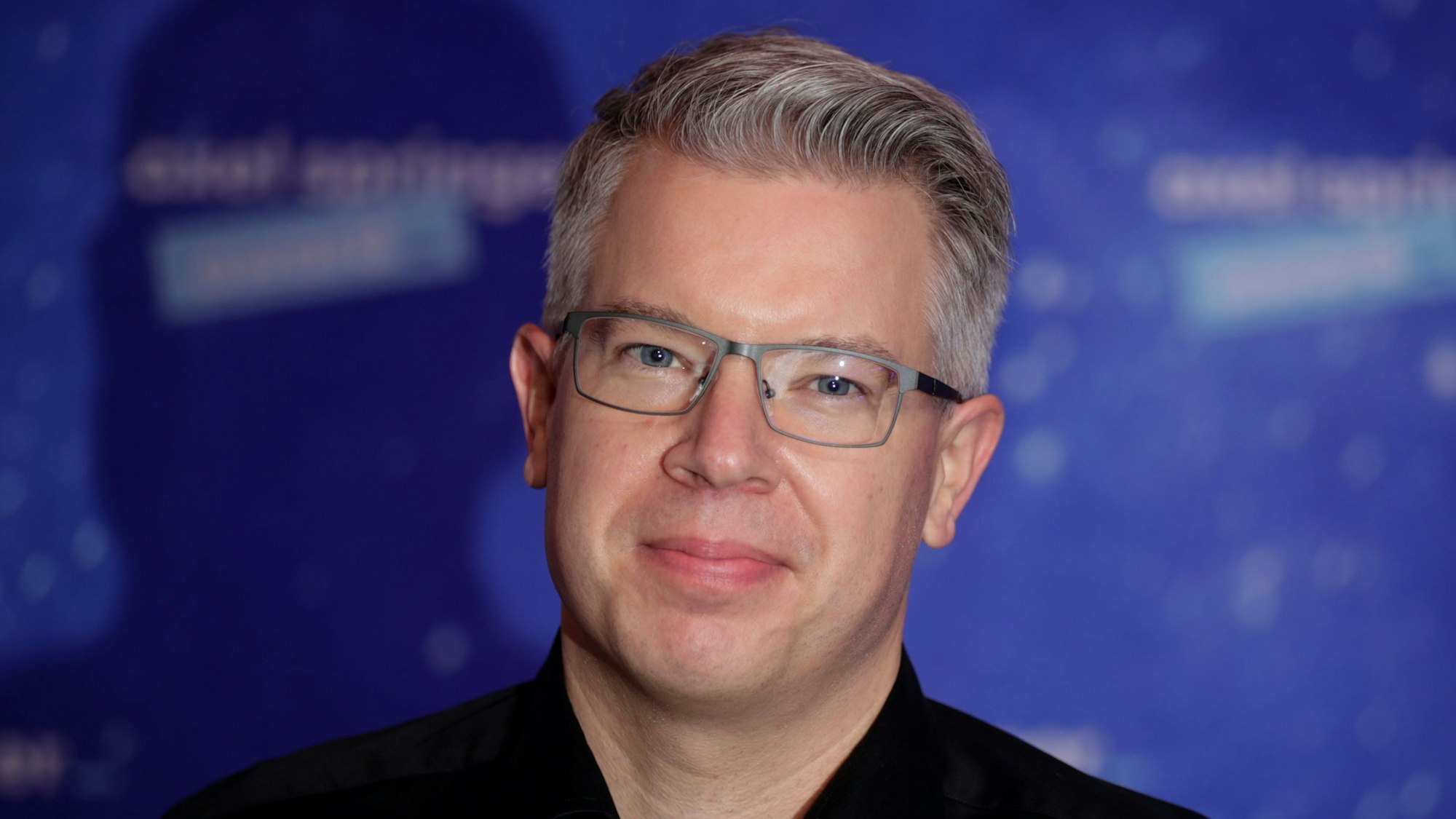 Frank Thelen, Unternehmer und bekannt aus „Die Höhle der Löwen“, blickt vor einem blauen Hintergrund in die Kamera.