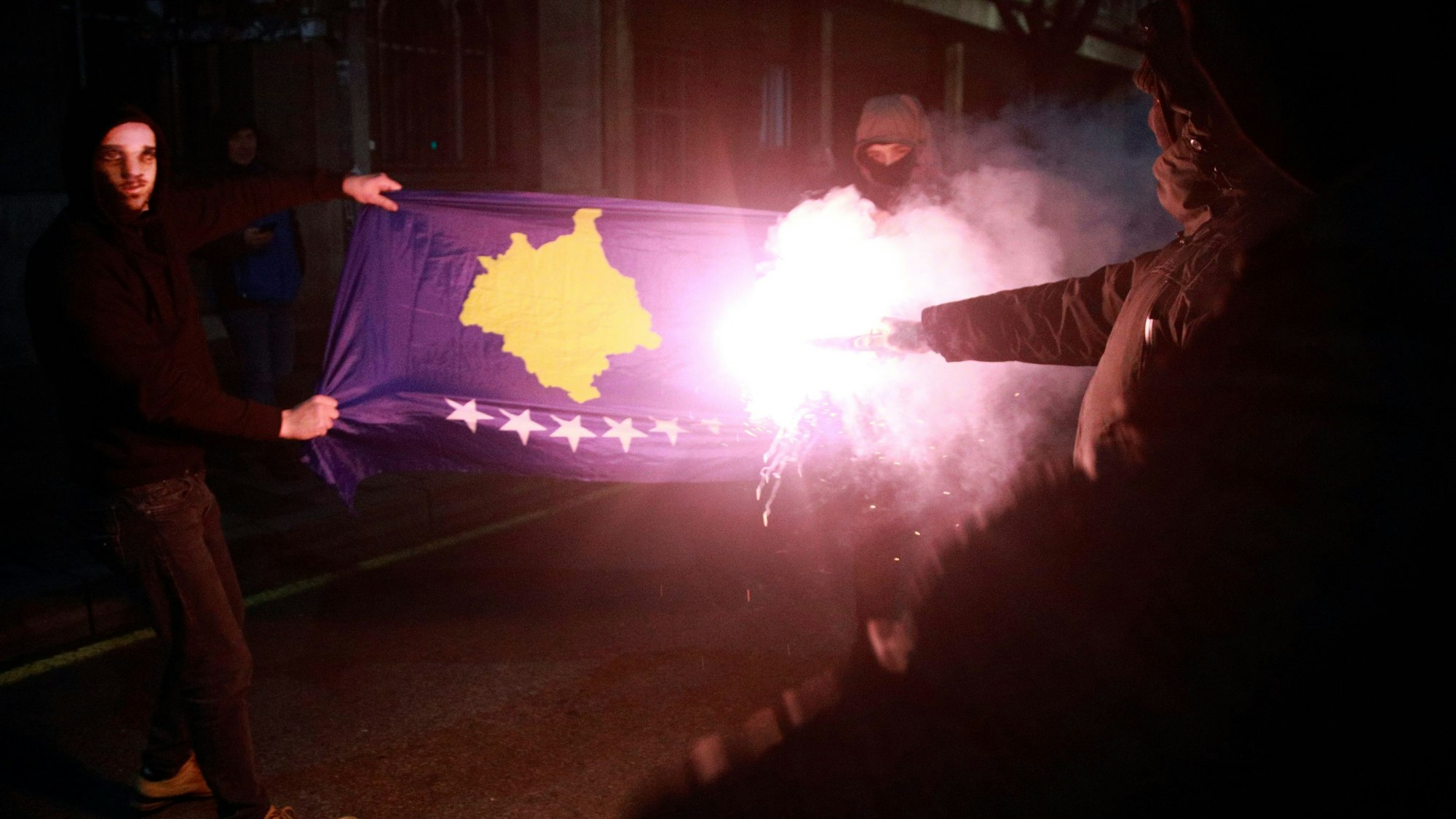 Maskierte Demonstranten verbrennen eine Fahne des Kosovo bei Demonstrationen in Belgrad.
