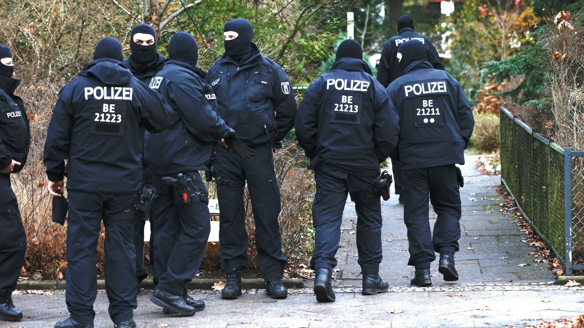 Vermummte Polizisten sind während der Razzia im „Reichsbürger“-Milieu in Berlin zu sehen, sie stehen vor einem Garteneingang.